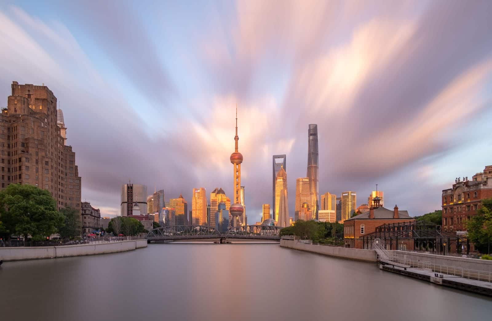 Shanghai Pudong skyline at sunset with the Oriental Pearl Tower and dramatic clouds over the Huangpu River